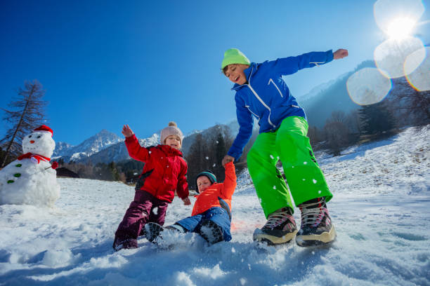 istock Children having winter fun jump together on sunny mountains 1993368393