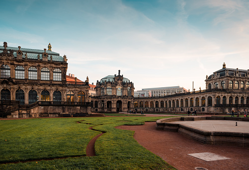 Dresden, Germany - December 08 2015: The Zwinger palatial complex with gardens at sunset. Baroque-styled architecture - view from inner yard with garden and fountain in the frame.