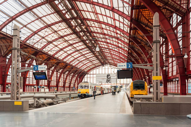 Antwerp, Belgium - December 06 2015: train hall of Antwerp Central Train Station. View of few platforms inside big airy train shed with burgundy-colored metal beams and train platforms below.