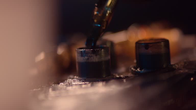 Extreme close-up of a tattoo machine. Needle going into a container to refill with ink