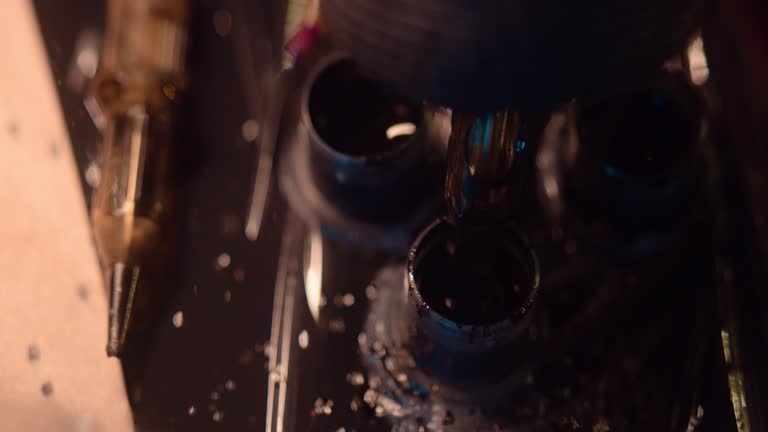 Extreme close-up of a tattoo machine. Needle going into a container to refill with black ink