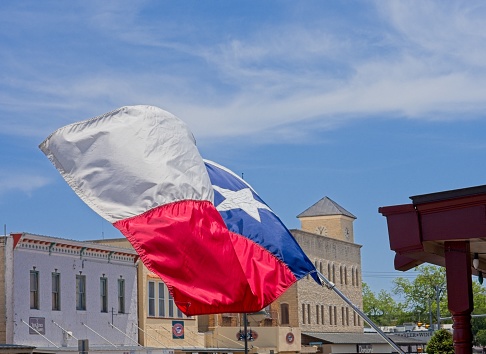 Fredericksburg, TX - USA, April 28, 2023. Texas state flag waves along Main street in old town Fredericksburg Texas.