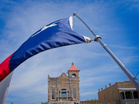 Fredericksburg, TX - USA, April 28, 2023. Texas state flag waves along Main street in old town Fredericksburg Texas.