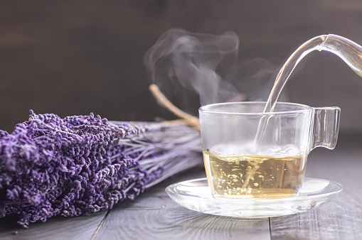 Cup of lavender tea with dried lavender flowers on rustic table, herbal relaxing tea. Lavendula oleum