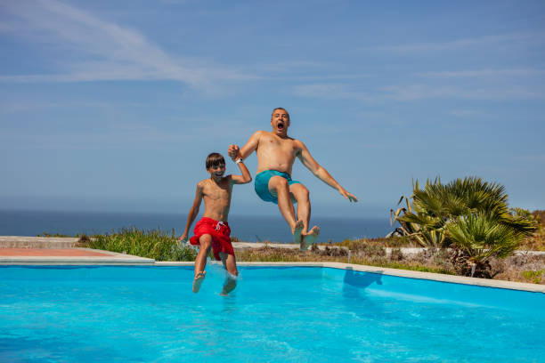 istock Pool jump with ocean view, dad and son summer fun on vacations 1993473983