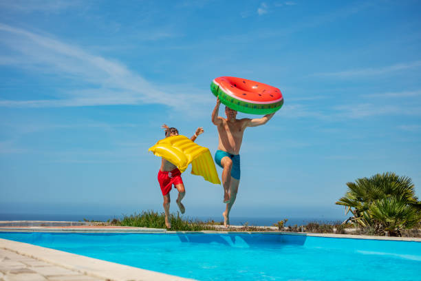 istock Dad and son with floaties jump to pool ready for summer fun 1993473986