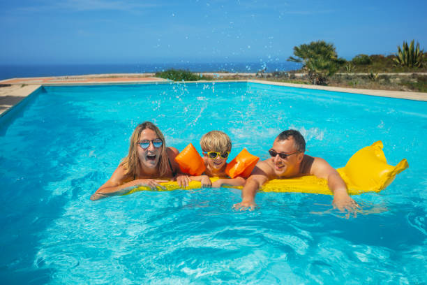 istock Happy parents with son enjoy pool time on summer vacations 1993474000