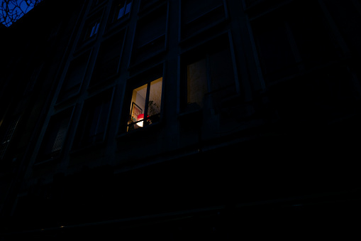 View from below at the light coming from one window on the tall apartment building