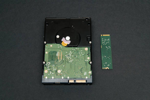 Comparing large HDD hard disk drive to small NVME SSD M2 disk from gray Comparing large HDD hard disk drive to small NVME SSD M2 disk from gray background solid state disk photos stock pictures, royalty-free photos & images