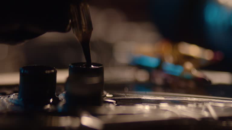 Close-up of a tattoo machine. Needle going into a container to refill with ink