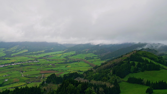 Cloudy mountain peaks landscape cinematic drone view. Gloomy weather green fields with rural houses slow motion. Grassy ridges nature under thunder sky. Countryside greenery hills with pine forest