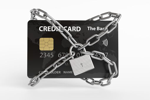 Black credit card being locked by silver metallic chains and a padlock on white background. Illustration of the concept of security of contactless payments, digital wallets, online transactions