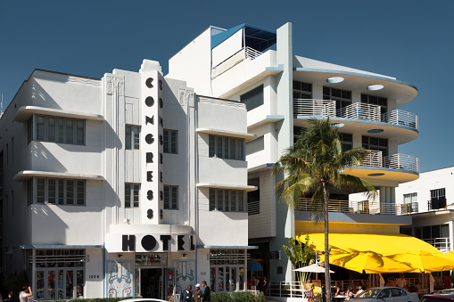 People walk past art deco style hotel on Ocean Drive, in the Art Deco District of Miami Beach Florida USA on a sunny day.