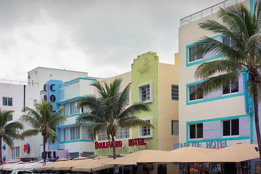 Hollywood Beach in north Miami, Florida colorful pastel blue house apartment building with Art Deco retro vintage style architecture looking up on palm tree, window and evening sky