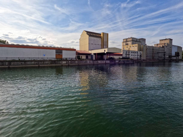 Industrial scene at the Port de Strasbourg in Strasbourg, France. Industrial buildings and equipment sit at the edge of the Rhine River.