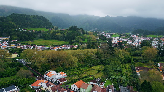 Countryside architecture at misty mountains aerial view. Panoramic nobody nature landscape with small village. Green pine trees forest at rural fog environment super slow motion. Vivid slopes scenic