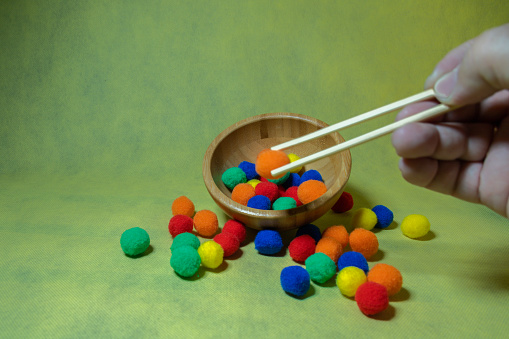 Using chopsticks to select colorful balls from a bowl, emphasizing decision-making and choice