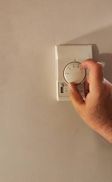 istock person using the thermostat placed on the wall to have an ideal temperature. 1993682196