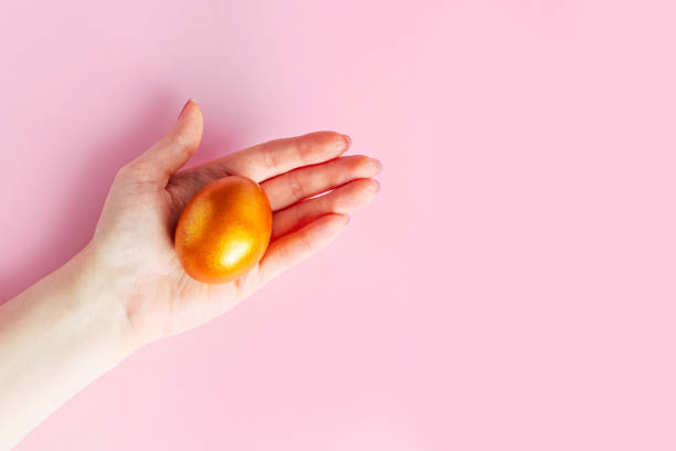 istock Woman holds a shiny Easter golden egg in her hand. 1993686881