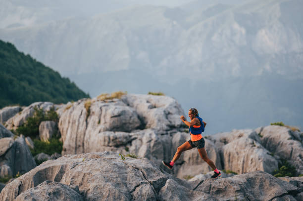 istock A female extreme runner is running on rocky mountain top. 1993697647