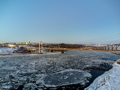 Aerial view of Quebec city bridges, the old bridge and the Pierre-Laporte bridge during dusk of winter with ice moving on the St. Lawrence river