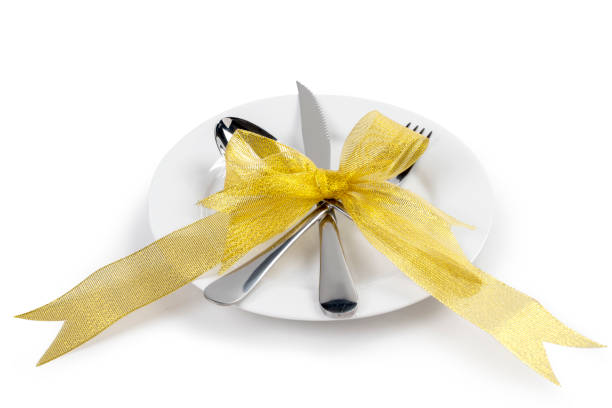 White plate with silverware of fork, knife, and spoon tied up on ribbon isolated over white background. Romantic dinner Valentine's Day concept