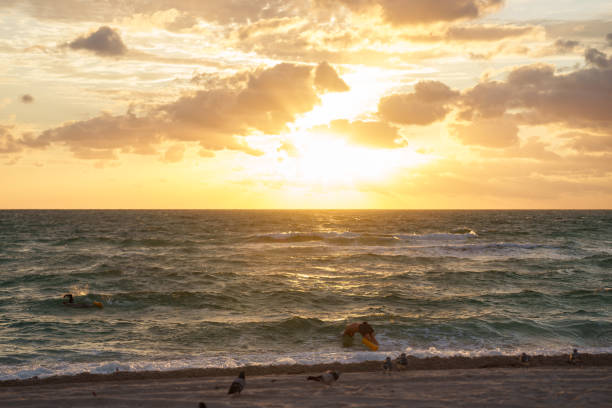 An unrecognizable man dives into the waves of the ocean enjoying a beautiful sunset on the coast of Florida.