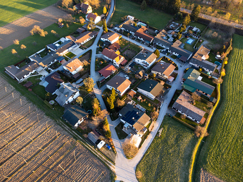 Aerial view of a quaint suburban neighborhood with houses and gardens at sunset, showcasing residential planning and community living.