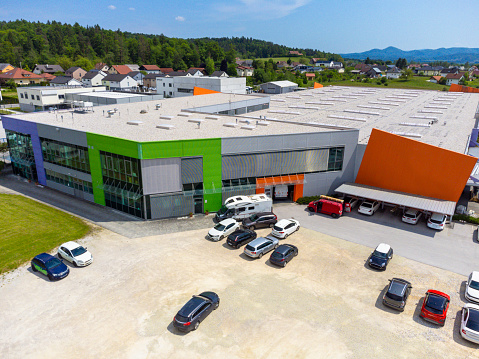 Aerial view of a modern commercial building with parking lot in a suburban area on a sunny day.