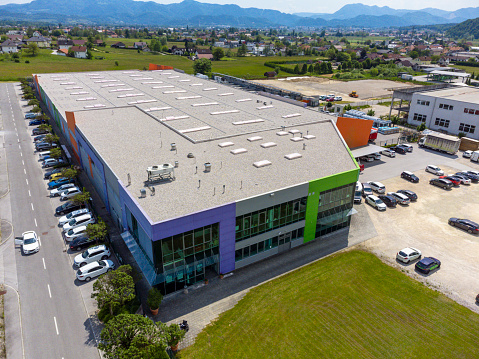 Aerial view of a modern commercial building with a spacious parking lot in a suburban setting.