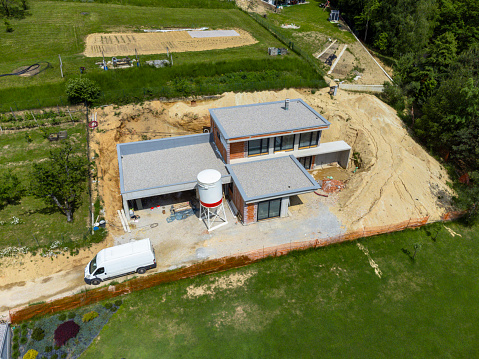 Aerial view of a residential construction site with a partially completed house and materials.