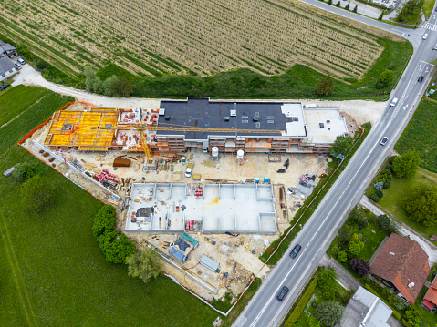 Aerial view of a construction site with machinery and partially completed buildings near a road.
