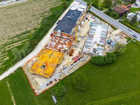 Aerial view of a construction site with machinery and building materials, surrounded by green fields.