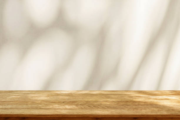 istock Empty wood table top on beige wall texture with tree leaves shadow background 1993775835