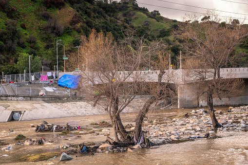 Glendale, CA, USA  February 7, 2024: After days of heavy rain, water flows through the flood control channel in the Glendale Narrows portion of the Los Angeles River in Glendale, CA.