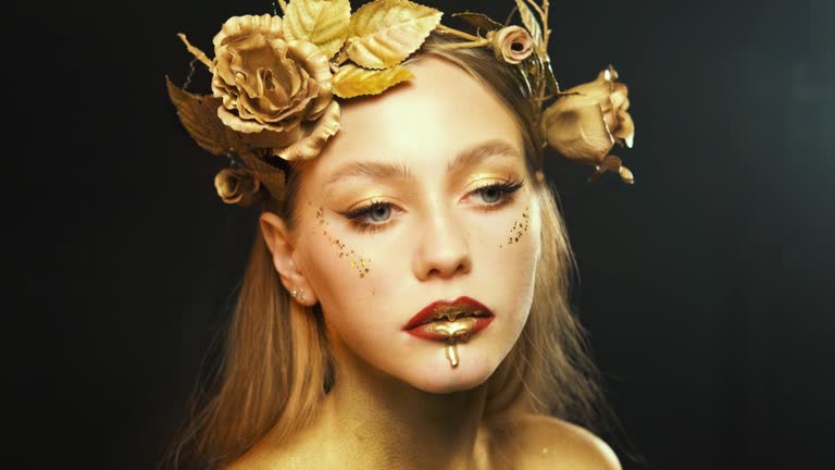 Portrait of fantasy woman in image of goddess Drops of gold paint drip dowl lips