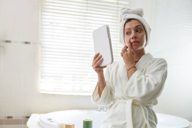 istock Woman with mirror touching her face 1993871937