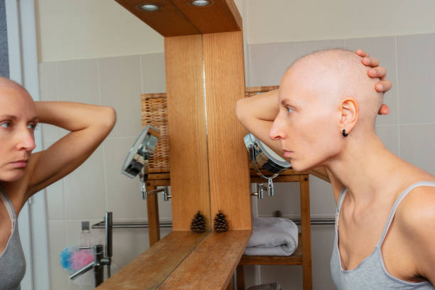 istock Bald lady with cancer stare reflectively at her own mirror image 1993876907