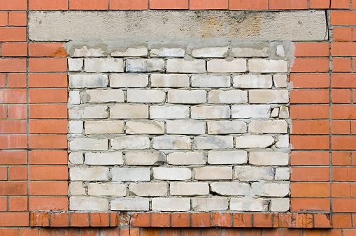 Old aged weathered red brick hut wall background, bricked-up shed window aperture, bricked-in white damaged calcium silicate sand lime bricks, grungy textured large detailed horizontal shack backdrop dirty vintage texture pattern, blank empty copy space