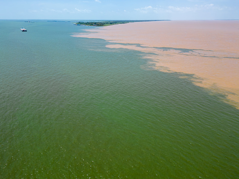 Aerial drone shot of majestic confluence of Tapajos (green water) and Amazon (muddy water) rivers in front of Santarem, Brazil.