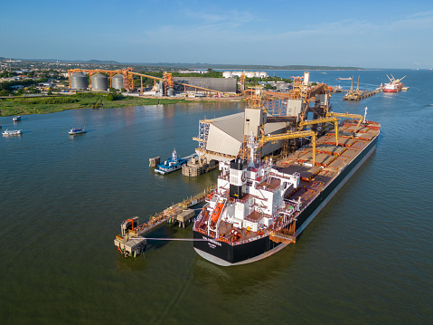 Santarem, Para, Brazil - Feb 05, 2024: Aerial view of a cargo ship moored at the grain loading terminal on the banks of the Tapajos river. Top view of the port area. Soy and corn export activities.