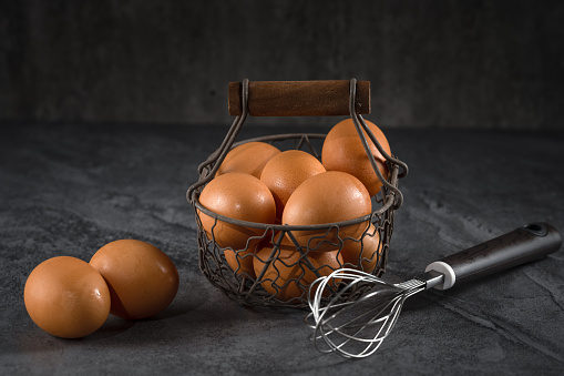 brown chicken eggs in a basket on a black background