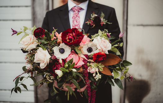 Wedding with groom holding bouquet of flowers