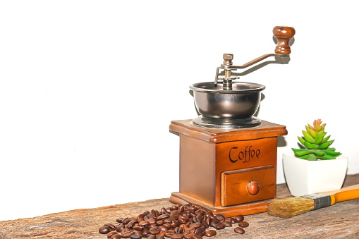 Brown coffee grinder and freshly roasted and grinded coffee beans on white background