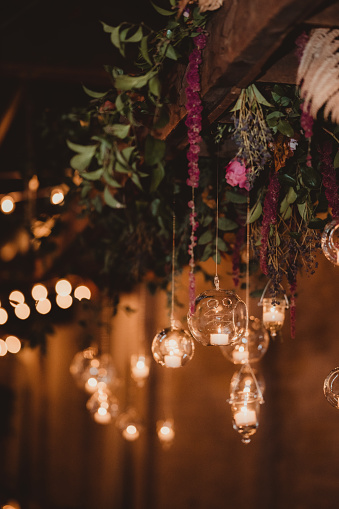 Candles in glass bulbs hanging with flowers