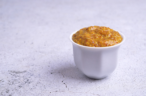 Traditional Bavarian mustard in a ceramic dish on a gray background. Selective focus.