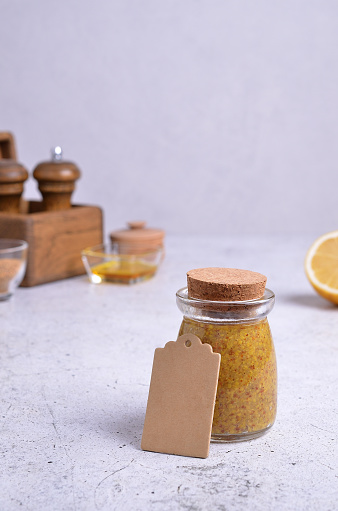 Traditional Bavarian mustard in a glass jar on a gray background. Selective focus.