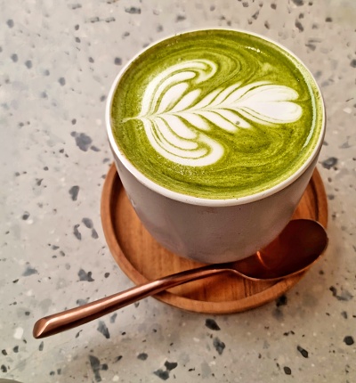 Jakarta, Indonesia - Feb 07, 2024: Hot Matcha green tea with Latte art in a grey cup