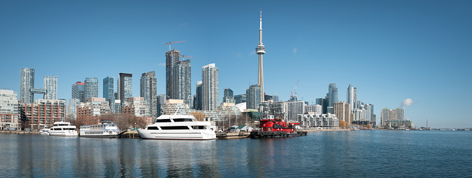 Toronto, Ontario, Canada, view of iconic Toronto skyline showing ferry boat arriving at Centre Island on a sunny day during fall season.