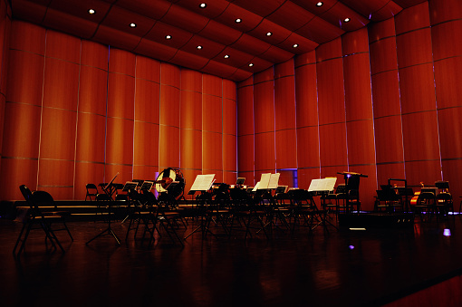 An empty symphony stage adorned with various symphonic instruments, awaiting the arrival of musicians to play magnificent musical compositions for the audience.